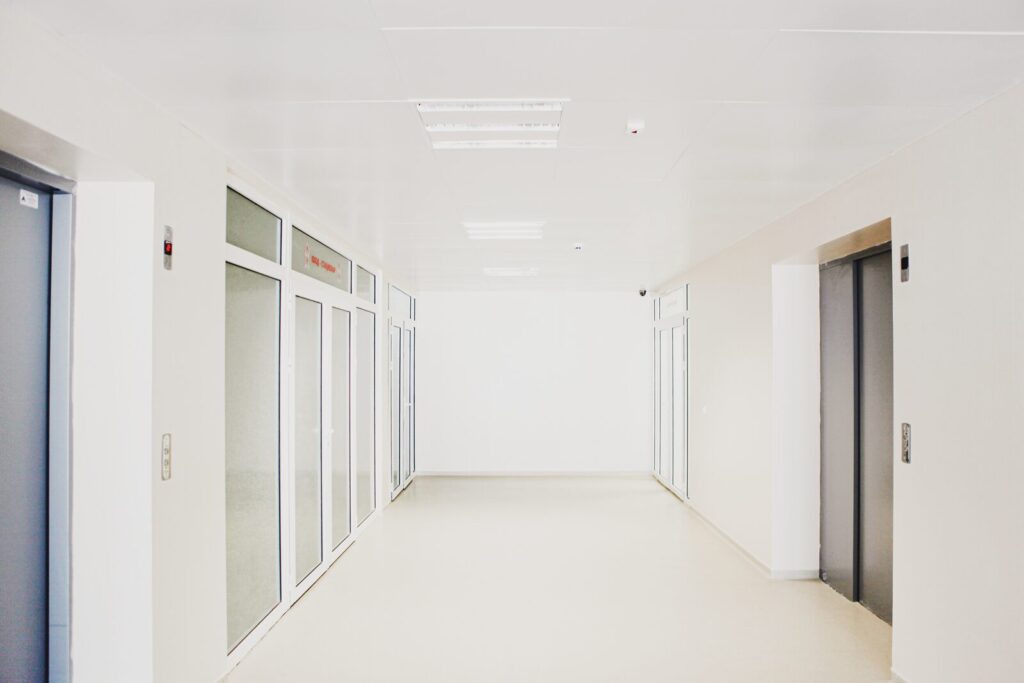 Bright, empty corridor with glass-panelled doors in a healthcare building